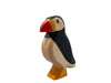 A Handmade Holzwald Puffin Bird figurine, painted in black, white, and yellow, standing upright on an orange base, isolated on a white background. This educational toy helps children learn about wildlife.