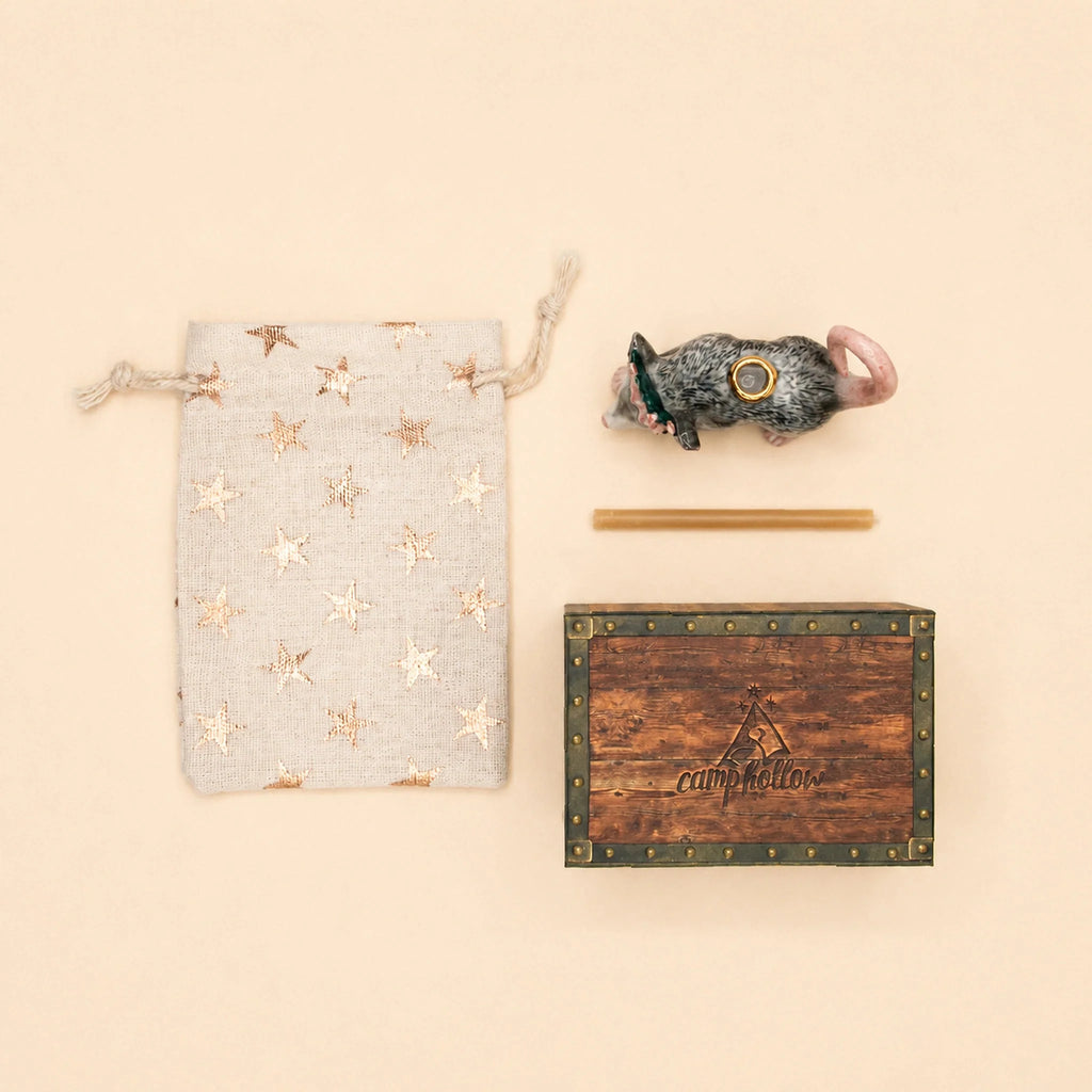 The Possum Cake Topper - Final Sale is charmingly displayed with a star-patterned drawstring bag, a toy mouse in a hat, a slender stick, and a wooden box featuring the “camphollow” name and tent logo—arranged on a beige background to evoke the delight of uncovering a hidden collectible keepsake or porcelain cake topper.