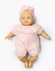 The Minikane Cuties Soft Body Doll (14") - Emilie with Clothing features closed eyes and a pink textured romper with matching bow headband—an adorable addition to any Minikane collection or paired with cute doll accessories.
