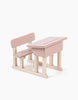 The Minikane Doll School Desk - Grey is a compact, artisan-crafted children's wooden school desk with an attached bench. The desk features a flat top with light wood legs, while the bench includes a backrest, all painted in a charming grey. The design is simple and perfect for playtime with Minikane Babies.