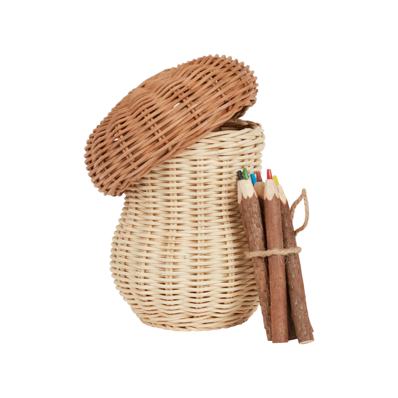 Olli Ella Mushroom Basket with a lid slightly ajar, next to a bundle of hand-carved wooden pencils tied with twine, isolated on a black background.