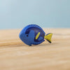 The Bumbu Handmade Wooden Royal Blue Fish is a small, sustainably crafted Montessori toy, painted blue with dark blue and yellow details. It stands upright on a wooden surface—a charming choice for imaginative play.