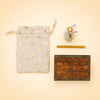 A Royal White Rabbit Cake Topper, a star-patterned pouch, a gold wax stick, and a keepsake treasure chest wooden box labeled “camp hollow” are arranged neatly on a beige background.