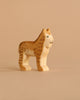 A Handmade Holzwald Lynx wooden toy figure with brown painted details stands on a plain beige background, highlighting the charm of sustainable toys.