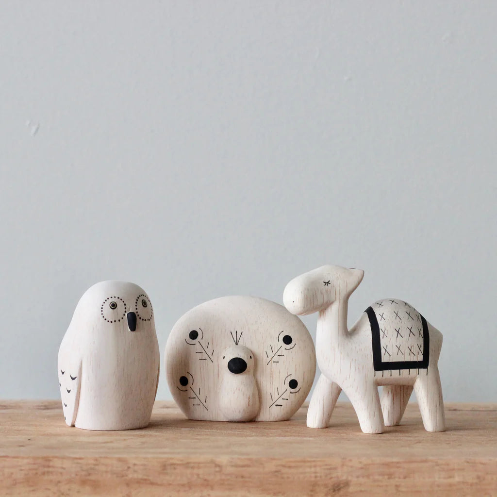 Four Handmade Tiny Wooden Exotic Animals - Peacock—a penguin, seal, polar bear, and camel—decorated with minimalistic patterns, standing on a wooden surface against a plain backdrop.