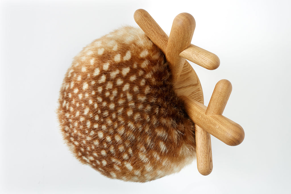 A round faux Bambi chair with a seat covered in faux fur and supported by wooden legs arranged in a star shape, photographed against a white background.