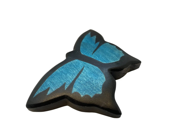 A high-quality Handmade Holzwald Butterfly with black edges and blue wings, featuring carved details for a textured look. The smooth, curved lines and natural wood grain patterns in the blue sections showcase artistry, perfect for those who appreciate sustainable toys.