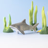 The Bumbu Handmade Wooden Shark Family Set features a wooden shark toy with green seaweed decorations and a small yellow fish on a light blue background—ideal for Montessori play or shark-themed collections.