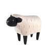 A Handmade Tiny Wooden Farm Animals - Sheep figurine crafted from Albizia wood, with a textured cream body, black face and legs, and simple facial features, isolated on a white background.