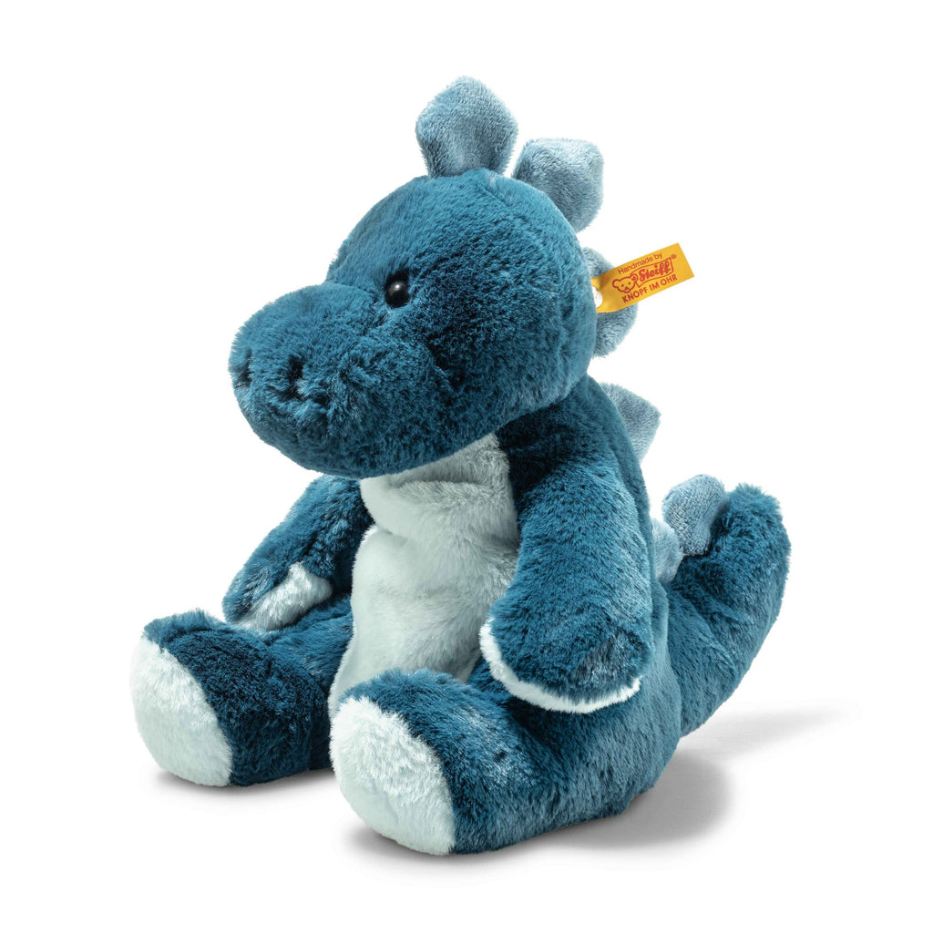 The Steiff Spott Stegosaurus Dinosaur is a plush blue and white toy with soft fabric, a rounded snout, embroidered eyes, small raised spikes on its head and back, sits upright, and has a yellow tag attached to its ear.