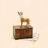 A Stag Cake Topper, offered as a final sale item, is displayed atop a vintage keepsake treasure chest resting on star-patterned light fabric against a plain beige background.