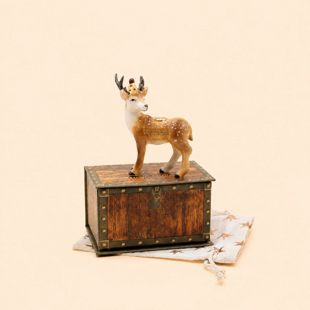 A Stag Cake Topper, offered as a final sale item, is displayed atop a vintage keepsake treasure chest resting on star-patterned light fabric against a plain beige background.