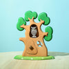 The Bumbu Handmade Wooden Ancient Oak Tree with Owl Set is a handcrafted wooden toy tree with green leaves, an owl in a hollow, white flowers on a green base, and a blue background.