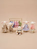 Five Little Forest Animals — The Bellevue Family, crafted from organic cotton dolls material and dressed in various outfits, stand and sit around a gold clothing rack adorned with miniature clothes, all set against a beige background.