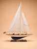 A detailed handcrafted "Little Forest Animals Silk Rug — The Regatta Series — The Endeavour," featuring elegant depictions of sailing yachts with white sails and a small American flag on the stern, displayed against a plain beige background.