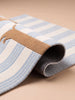 A close-up of the Little Forest Animals Silk Rug — The Dachshund, featuring blue and white stripes and a brown dachshund design, rolled up and displayed on a beige surface.