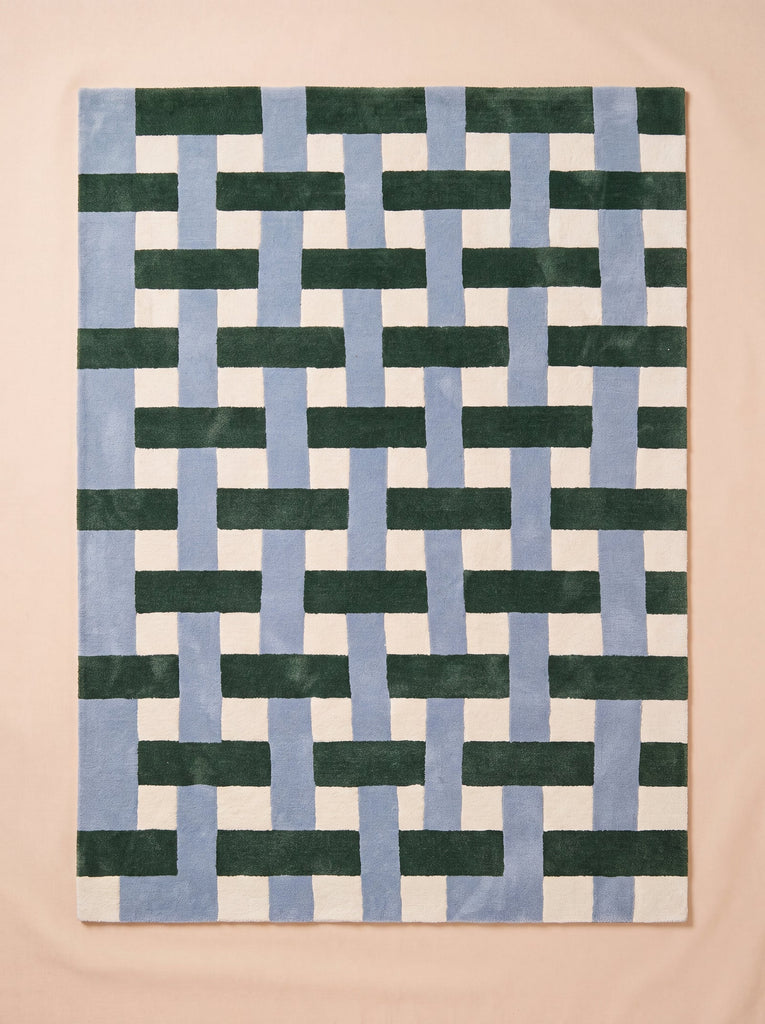 The Little Forest Animals Silk Rug — The Weave is a designer area rug with a square shape, showcasing an interwoven geometric pattern of blue, green, and white rectangles on a light beige background for a woven effect.