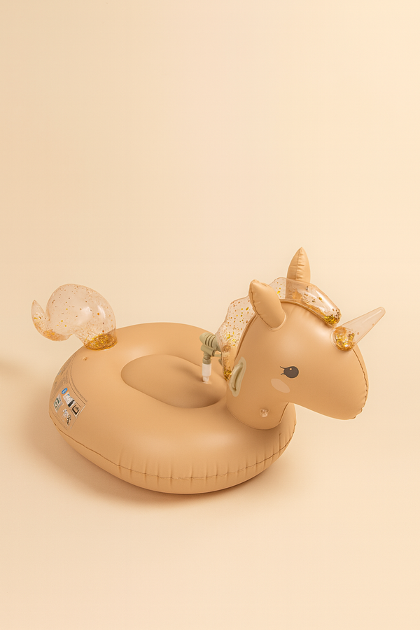 The Inflatable Water Splasher Float - Unicorn is a tan kids pool float with a sparkly tail, mane, horn, and cute cartoon eyes and ears, making it stand out against a beige background.