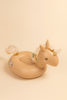 The Inflatable Water Splasher Float - Unicorn is a tan kids pool float with a sparkly tail, mane, horn, and cute cartoon eyes and ears, making it stand out against a beige background.