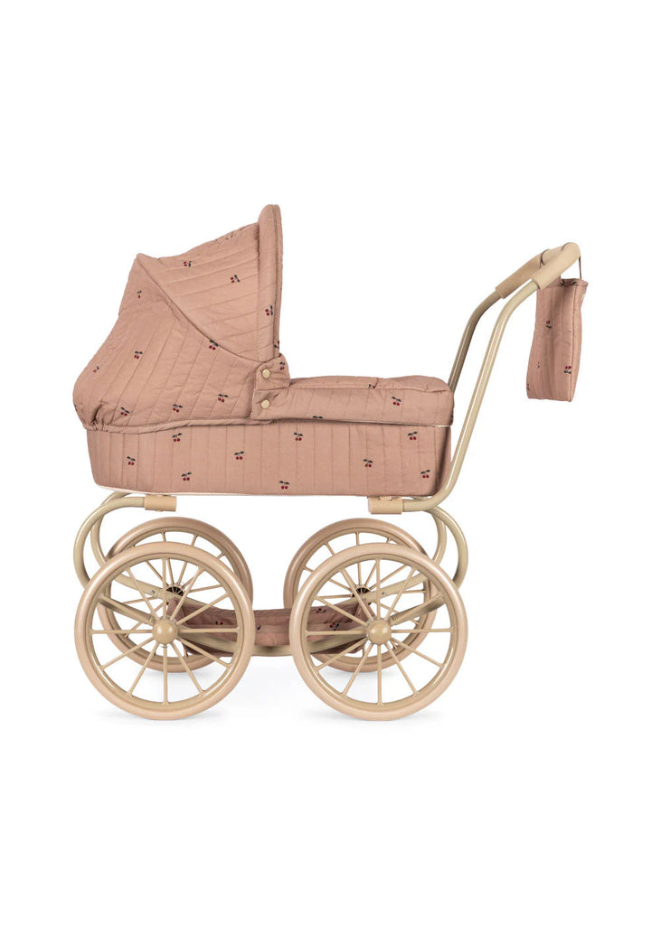 The Konges Sloejd Mini Doll Pram in Cherry Blush features a quilted dusty pink cover, beige frame, four large spoked wheels, and a matching bag attached to the handle—a charming vintage-inspired toy pram.