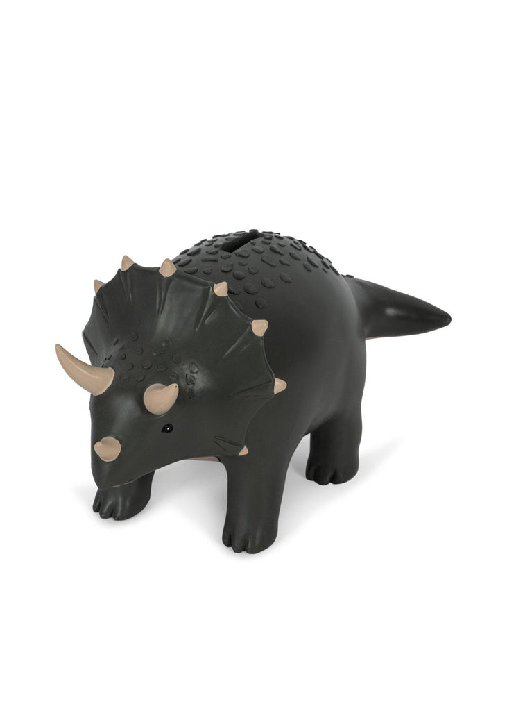 The Konges Sloejd Money Bank - Dino features a dark green triceratops with beige horns and spots, standing on four legs. The coin slot is on its back, making saving fun and easy for kids.