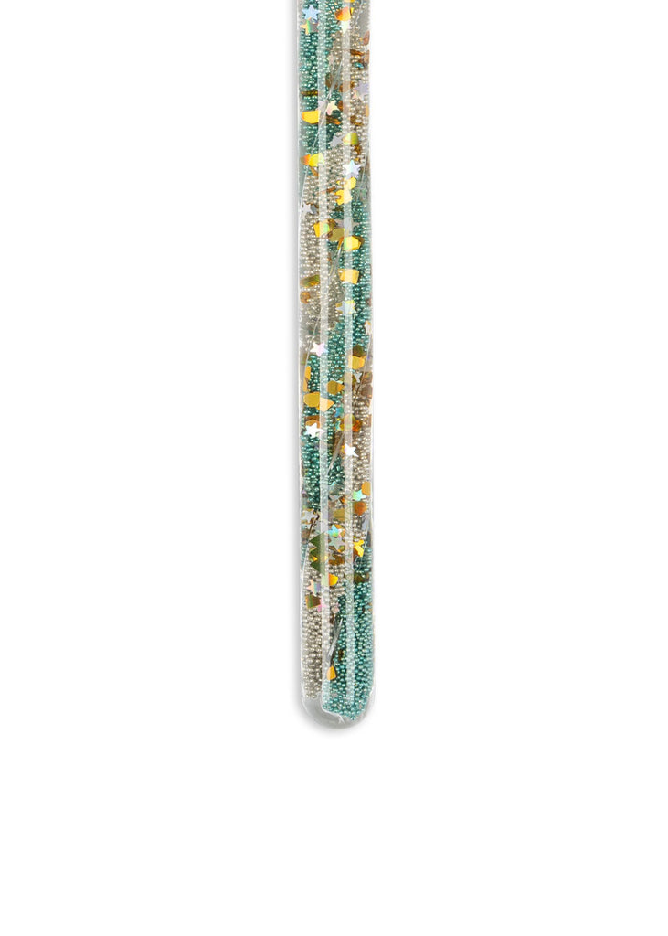 The Konges Sloejd Magical Glitter Wand - Green Mix is a clear glass rod filled with colorful beads and glitter in teal, gold, and silver, shown standing vertically against a white background.