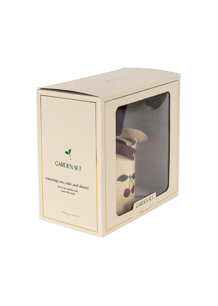 The Konges Sloejd Garden Set is a cream-colored box with a clear window showing a cherry-print watering can. This kids gardening set includes a watering can, rake, and shovel—ideal beginner tools for little hands.