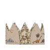 The Konges Sloejd Birthday Crown - Dino features cotton fabric with pointed peaks, embroidered dinosaurs, trees, stars, a crescent moon, and a volcano in earthy tones on a beige background.