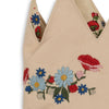 A close-up of the Konges Sloejd Birthday Crown - Flower, a beige fabric crown adorned with colorful embroidered blue daisies, red poppies, white flowers, and green leaves along the base and tips.