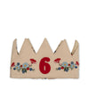The Konges Sloejd Birthday Crown - Flower is a beige fabric crown-shaped headband with red, blue, and yellow embroidered flowers and a bold red number 6 at the center.