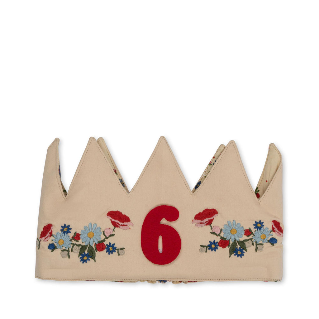 The Konges Sloejd Birthday Crown - Flower is a beige fabric crown-shaped headband with red, blue, and yellow embroidered flowers and a bold red number 6 at the center.