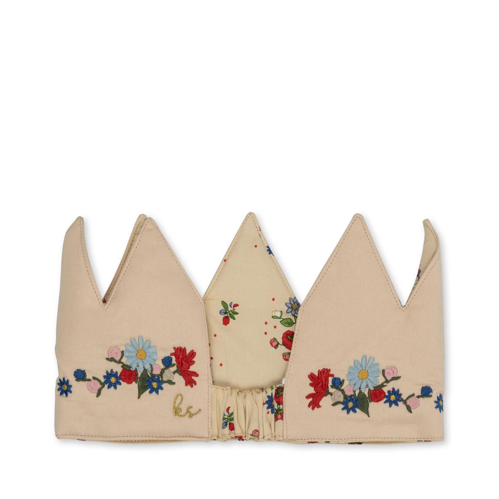 The Konges Sloejd Birthday Crown - Flower is a soft beige crown with three points, colorful embroidered flowers, a gold monogram, floral print lining, and elastic back for an adjustable fit.