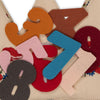 A pile of colorful felt numbers (3-8) overlaps on a beige, floral-embroidered fabric—the Konges Sloejd Birthday Crown - Flower, perfect for decorating a birthday crown or hat.