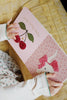 A child in white pajamas holds an open Konges Sloejd Touch and Feel Book - Unicorn, showing pink pages with a unicorn illustration and textured details.
