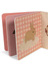 The Konges Sloejd Touch and Feel Book - Unicorn is open, revealing a page with a unicorn illustration on a soft cloud set against a pink checkered background dotted with small golden stars.