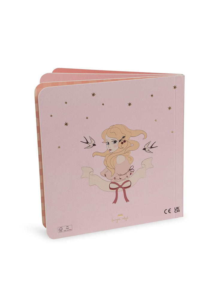 The Konges Sloejd Touch and Feel Book - Unicorn is a pink sensory baby board book with an illustration of a girl with long blonde hair, two birds, gold stars, and a ribbon. It features rounded corners and can stand upright.