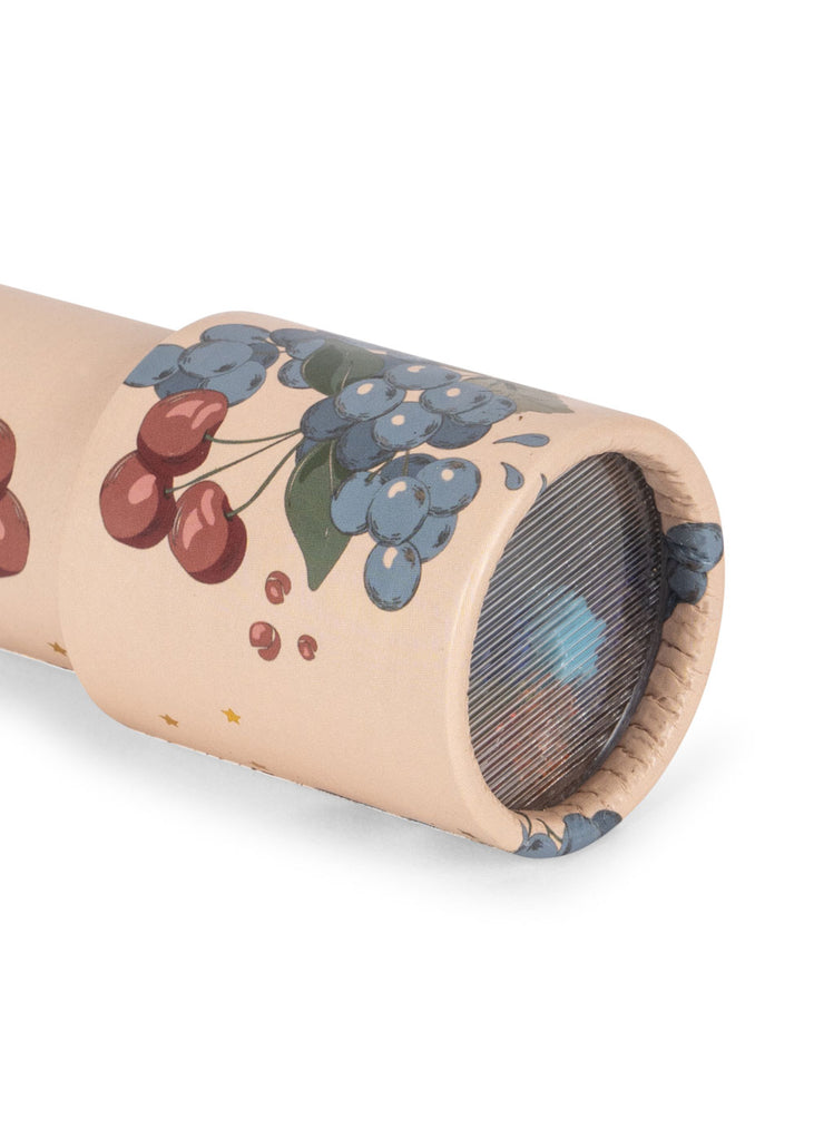 A close-up of the Konges Sloejd Kaleidoscope - Cremona, an FSC-certified beige kaleidoscope featuring red cherry and blue grape illustrations, with a blue geometric pattern visible through the lens end.