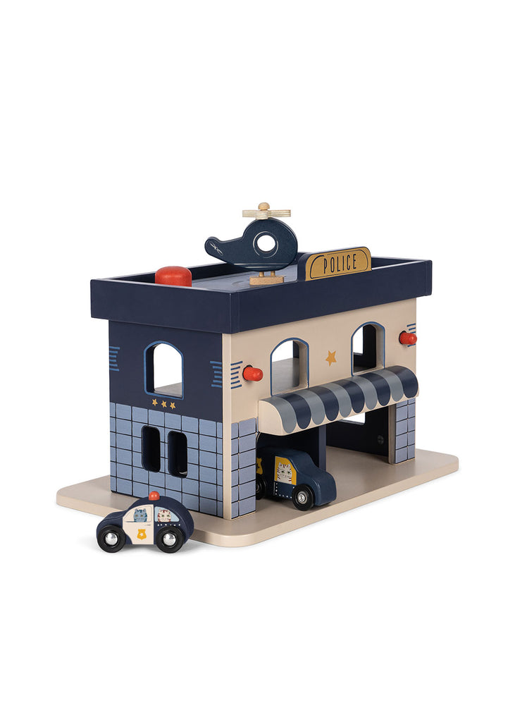 The Konges Sloejd Wooden Police Station is made from FSC-certified wood and features a blue and gray station with a striped awning, "POLICE" sign, toy helicopter on the roof, plus police car and van.
