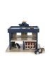 The Konges Sloejd Wooden Police Station is made from FSC-certified wood and features a blue and beige garage, a rooftop toy helicopter, two police cars, a jail door, and an illustrated sign.
