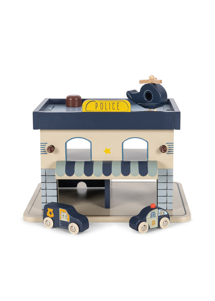 The Konges Sloejd Wooden Police Station, crafted from FSC-certified wood, features a yellow "POLICE" roof sign, two toy cars out front, a small helicopter on top, and comes in grey, blue, and beige colors.