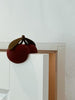 The Konges Sloejd Door Stopper - Cherry, shaped like two red cherries with green leaves, sits on a white door. This CE-tested silicone doorstopper holds the door ajar, allowing gentle light to pass through from the next room.