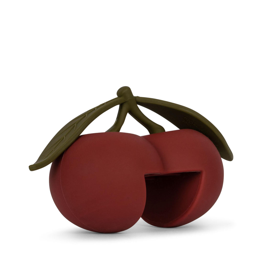 The Konges Sloejd Door Stopper - Cherry features two red cherries with green stems and leaves, one with a cut-out section. CE-tested and made from durable silicone, it’s both functional and decorative. Set against a plain white background.