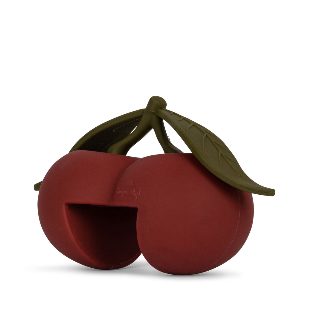 The Konges Sloejd Door Stopper - Cherry features a playful, deep red cherry design with green stems and leaves, a pet-friendly opening, CE-tested for safety—all set against a white background.
