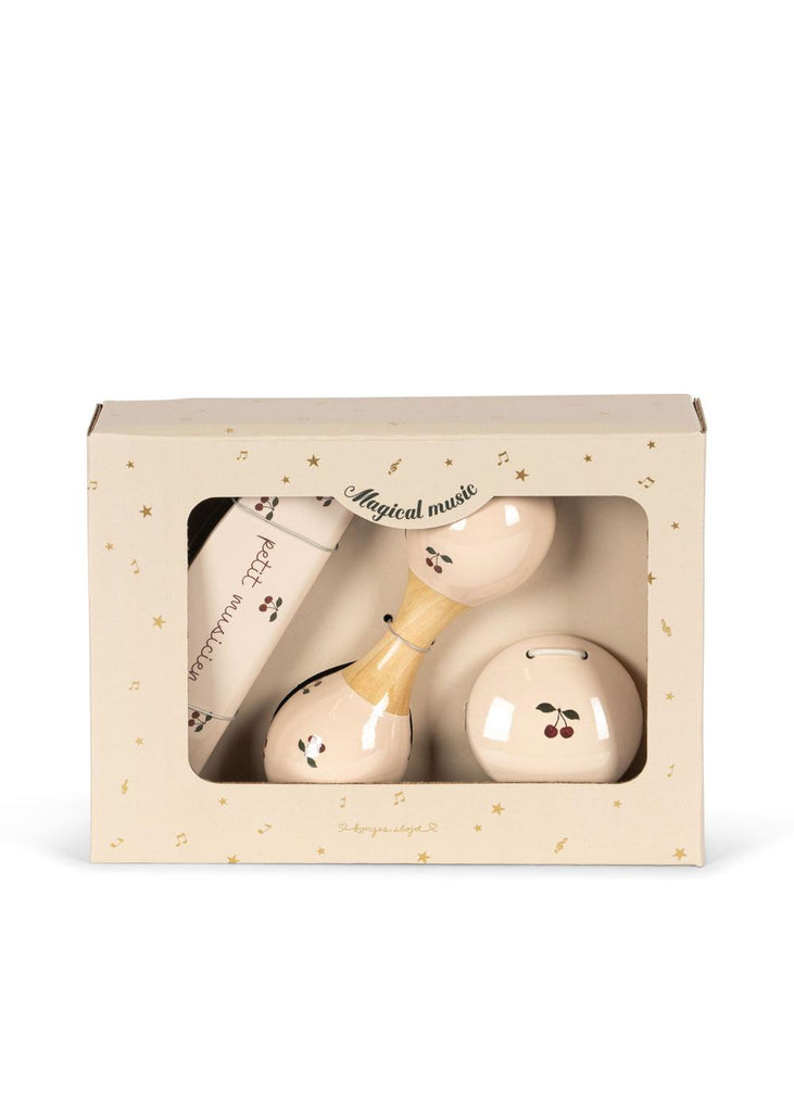 The Konges Sloejd Petit Music Set - Glossy Cherry is a boxed kids' musical instrument set with a cherry design, featuring wooden maraca, bell, and shaker visible through a clear window on the "Magical music" packaging.