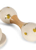 A Konges Sloejd Petit Music Set - Glossy Lemon maraca for kids features cream-colored rounded ends with yellow lemons and green leaves; a matching wooden instrument from the set appears in the lower left corner.