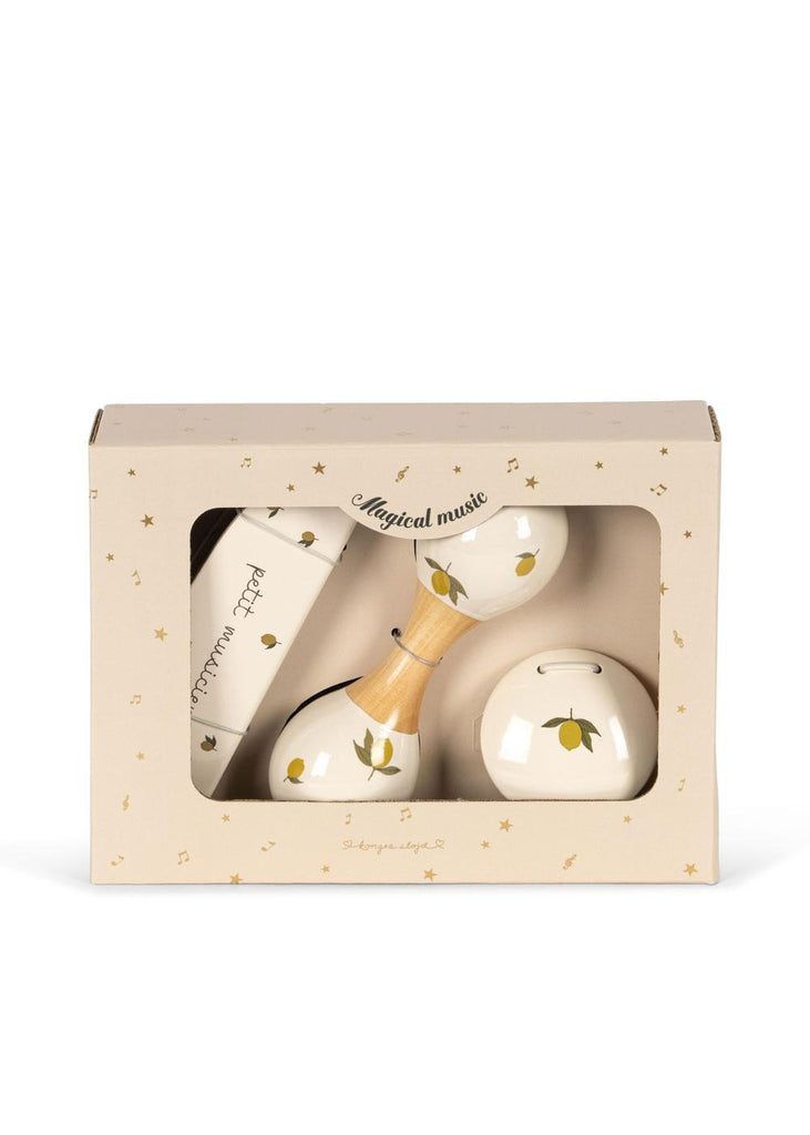The Konges Sloejd Petit Music Set - Glossy Lemon comes in a beige gift box labeled "Magical music," featuring maracas, a harmonica, and a round shaker—all wooden instruments with yellow lemon illustrations, visible through a clear window.