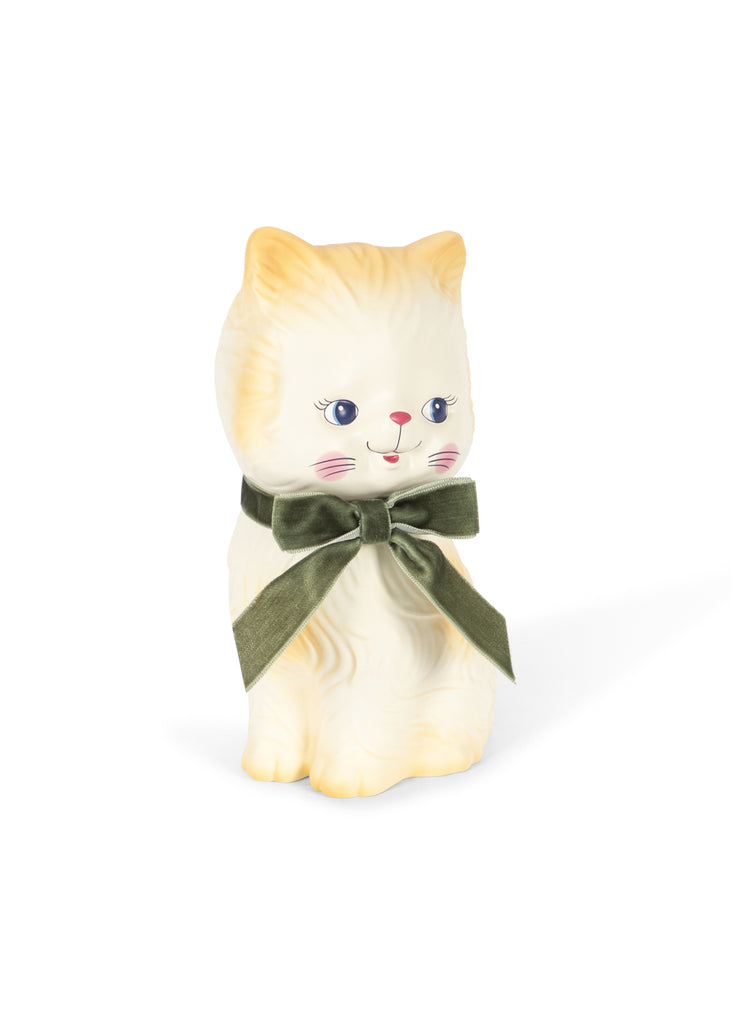 A cream-colored ceramic “Konges Sloejd Money Bank - Kitty” figurine with blue eyes and a pink nose, adorned with a large green velvet bow around its neck, sits on a white background. This charming hand-painted money bank adds both whimsical style and function to your decor.