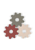 Three gear-shaped objects in gray, red, and beige overlap on a white background. Each has a circular hole in the center and rounded edges, resembling playful gears or toy parts—perfect components for the Konges Sloejd Tool Bench to inspire creative play with wooden toys.