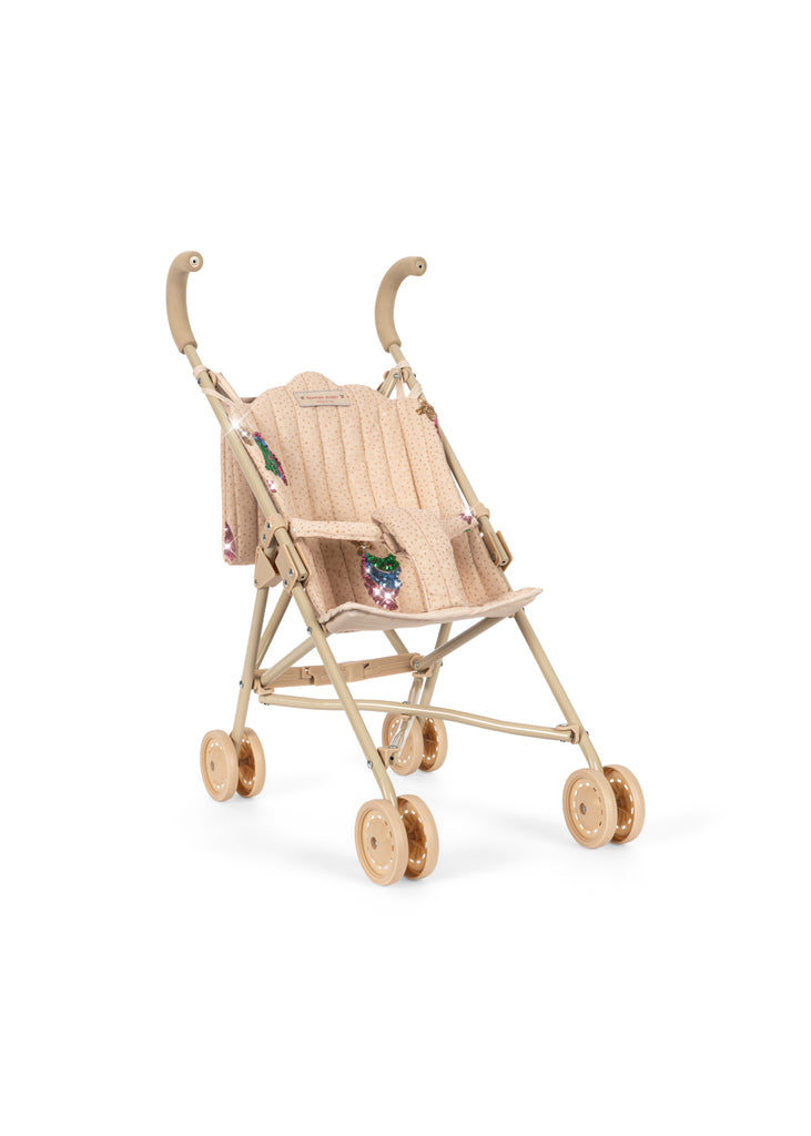 Konges Sloejd Tulle Doll Stroller - Rainbow Star features a beige design with curved handles, a gold-tone frame, and four sets of double wheels. The stroller has a textured seat adorned with embroidered floral patterns and is shown empty against a white background.