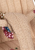 Close-up of the Konges Sloejd Tulle Doll Stroller - Rainbow Star, showing padded beige fabric adorned with gold polka dots and blue and pink sequins, featuring quilted stitching and straps, possibly part of the stroller’s seat with double wheels.